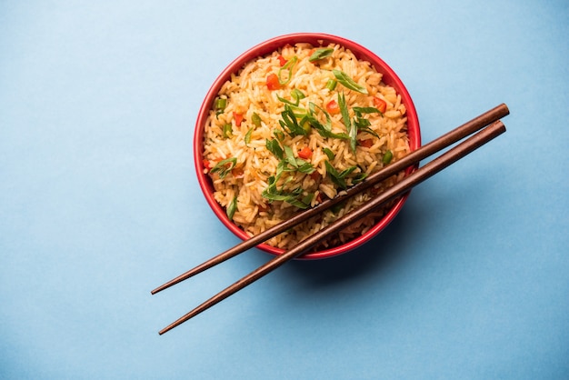 Schezwan Fried Rice Masala is a popular indo-chinese food served in a plate or bowl with chopsticks