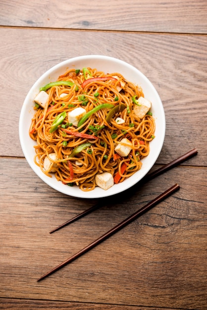 Schezwan hakka noodles with paneer or cottage cheese. Served in a bowl. selective focus