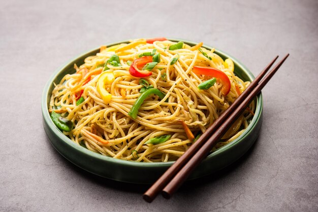 Schezwan noodles or szechwan vegetable hakka noodles or chow\
mein is a popular indo-chinese recipes, served in a bowl or plate\
with wooden chopsticks