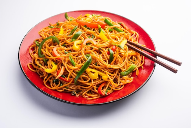 Schezwan noodles or szechwan vegetable hakka noodles or chow\
mein is a popular indo-chinese recipes, served in a bowl or plate\
with wooden chopsticks