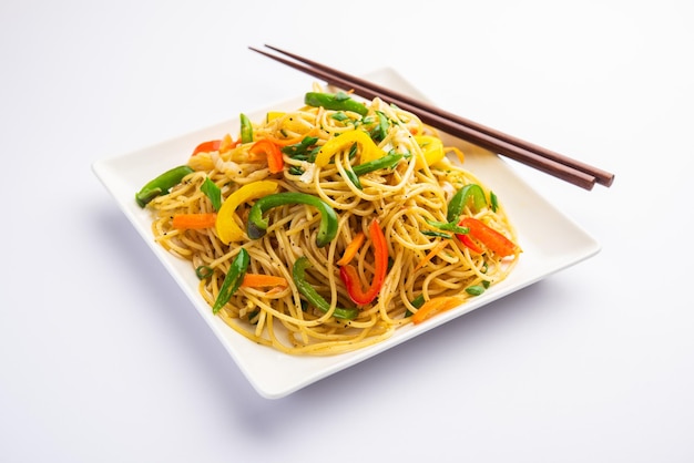 Schezwan noodles or szechwan vegetable hakka noodles or chow\
mein is a popular indo-chinese recipes, served in a bowl or plate\
with wooden chopsticks