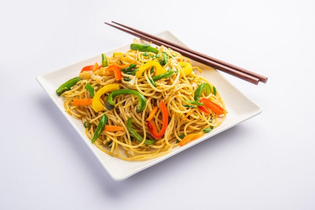 Schezwan noodles or szechwan vegetable hakka noodles or chow\
mein is a popular indo-chinese recipes, served in a bowl or plate\
with wooden chopsticks