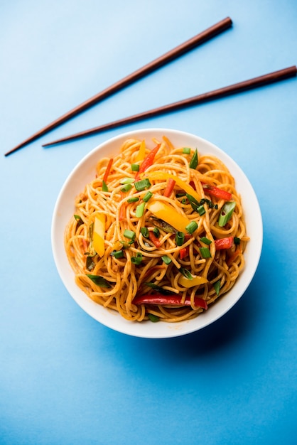 Schezwan Noodles 또는 야채 Hakka Noodles 또는 chow mein은 인기 있는 인도-중국 요리법으로 나무 젓가락으로 그릇이나 접시에 제공됩니다.