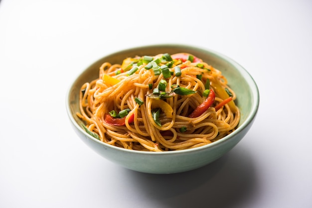 Schezwan Noodles or vegetable Hakka Noodles or chow mein is a popular Indo-Chinese recipes, served in a bowl or plate with wooden chopsticks