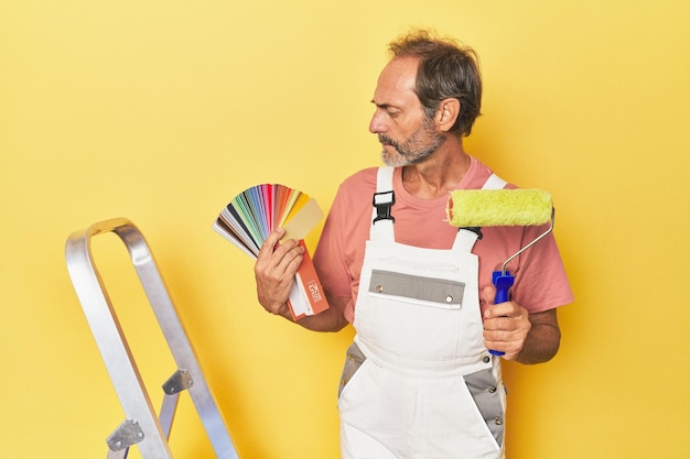 Foto schilder met roller en palet op ladder