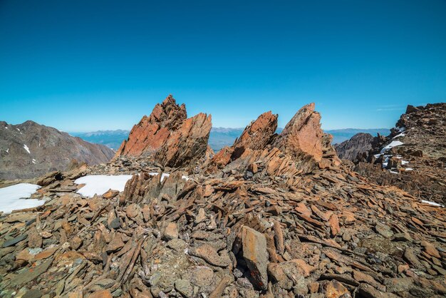 Schilderachtig berglandschap met oude rotsen en stenen tussen sneeuw in zonlicht Geweldig berglandschap met stenen uitschieters op hoge berg onder blauwe lucht op zonnige dag Scherpe rotsen op zeer grote hoogte