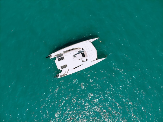 Schilderachtig bovenaanzicht van een enorme witte catamaran die over de diepe zee vaart. Luchtfoto.