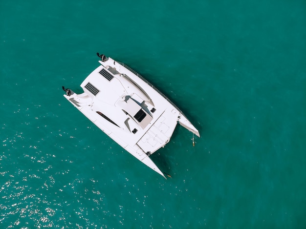 Schilderachtig bovenaanzicht van een enorme witte catamaran die over de diepe zee vaart. Luchtfoto.