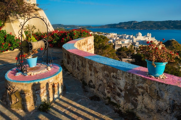 Schilderachtig schilderachtig uitzicht op de Griekse stad Plaka op het eiland Milos over rode geraniumbloemen