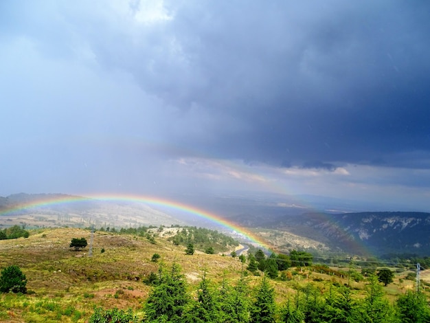 Schilderachtig uitzicht op een dubbele regenboog op het landschap tegen een bewolkte hemel