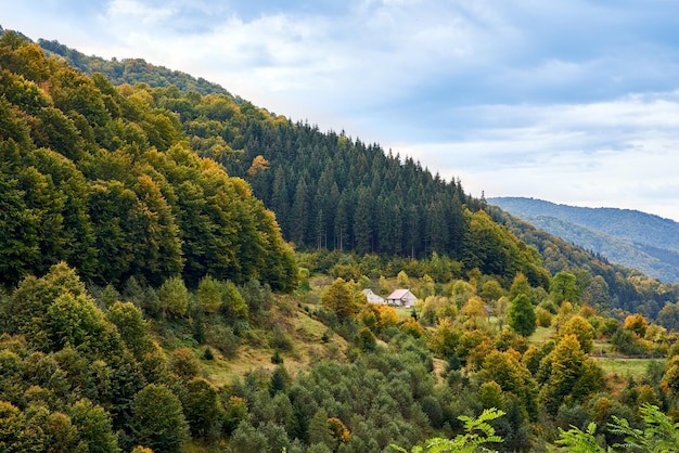 Schilderachtig uitzicht op een huis in een landschap vol bomen tegenover een bergketen