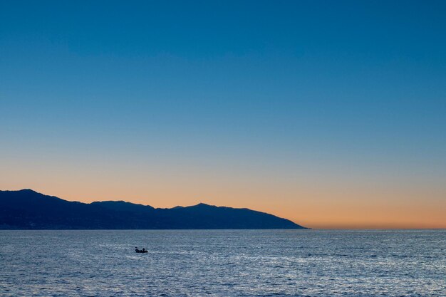 Schilderachtig uitzicht op een oranje hemel bij zonsondergang in een rustige baai met het silhouet van een eenzame kajak TrabzonTurkije