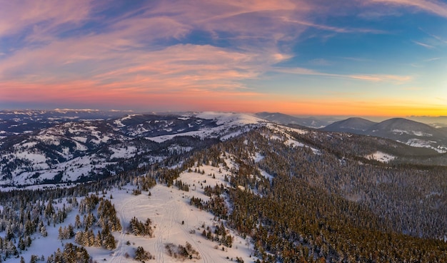 Schilderachtig winterpanorama van bergheuvels bedekt met sneeuw en sparren op een zonnige heldere dag met de zon en de blauwe lucht. Ongerept natuurschoonheidsconcept