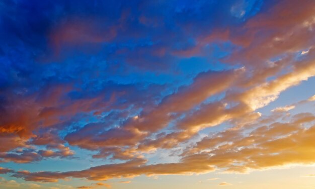 Schilderachtige wolken in een oranje en blauwe lucht bij zonsondergang