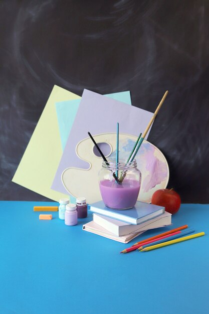 Schilderen leermiddelen boeken appel op tafel tegen schoolbord achtergrond terug naar school