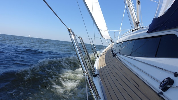 Schip zeilt op zee tegen een heldere blauwe hemel.