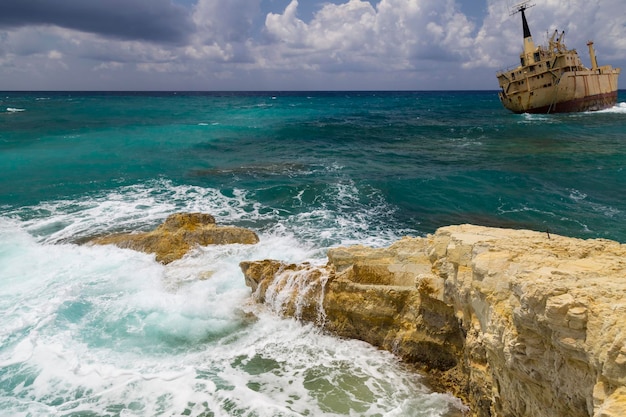 Schipbreuk Schip op de rotsen in de buurt van de kust turquoise zee met golven op de achtergrond van bewolkte hemel Kliffen in het water De Middellandse Zeekust in de buurt van Paphos Cyprus Zeegezicht Toeristische bestemming