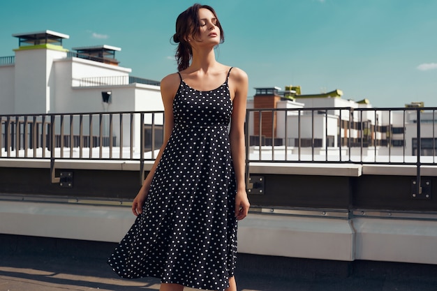 Schitterend helder brunette in manierkleding het stellen op het dak van een gebouw