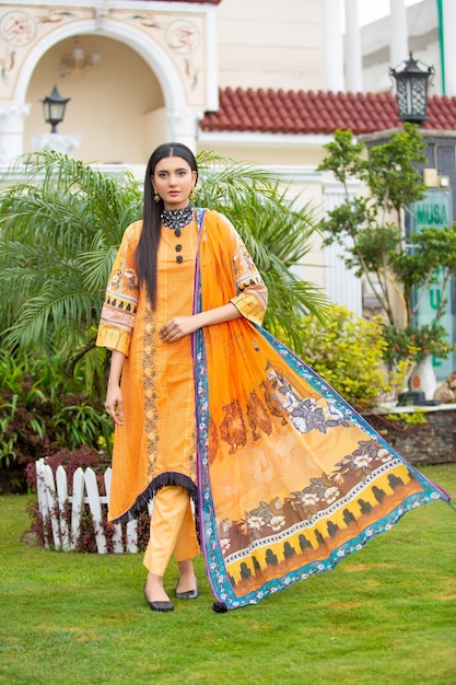 Schitterend jong meisje poseert vooraan in traditionele kleding voor fotoshoot in de tuin