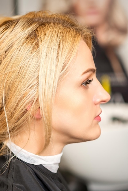 Schitterend profiel van kaukasische schoonheidsblonde vrouw met mooi kapsel over de achtergrond van de kapsalon.