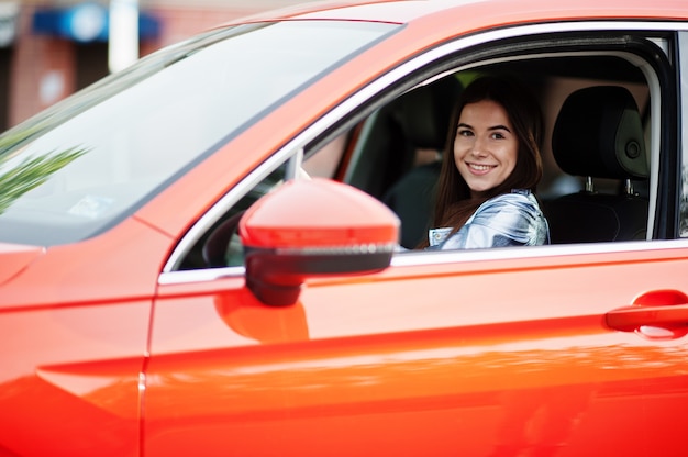 Schitterende vrouw die oranje suv-auto bestuurt