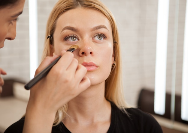 Schitterende vrouw die professionele make-up krijgt