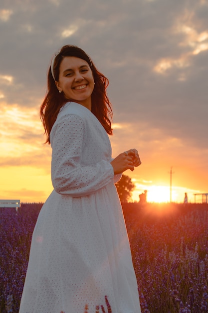 Schitterende vrouw in witte jurk bij zonsondergang in het lavendelveld