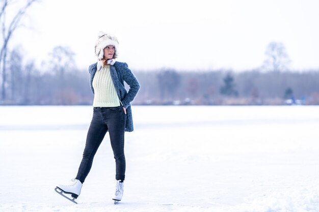 Schitterende vrouw schaatsen op bevroren meer in de winter