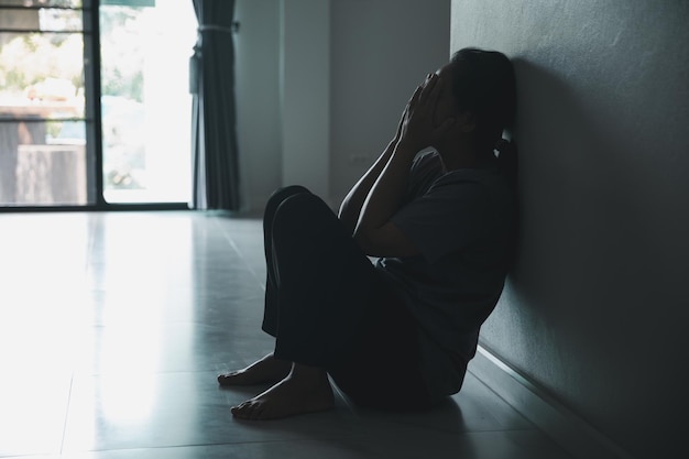 Schizofrenie met eenzaam en verdrietig in de geestelijke gezondheid depressie concept Depressieve vrouw die thuis tegen de muur zit met een schaduw op de muur die zich ellendig voelt Vrouwen zijn depressief, angstig en ongelukkig