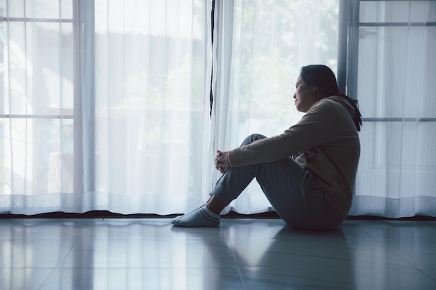 Foto schizofrenie met eenzaam en verdrietig in de geestelijke gezondheid depressie concept depressieve vrouw die thuis tegen de vloer zit met een donkere kamer die zich ellendig voelt vrouwen zijn depressief, angstig en ongelukkig