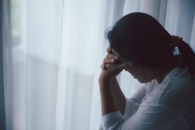 Foto schizofrenie met eenzaam en verdrietig in de geestelijke gezondheid depressie concept depressieve vrouw die thuis tegen de vloer zit met een donkere kamer die zich ellendig voelt vrouwen zijn depressief, angstig en ongelukkig