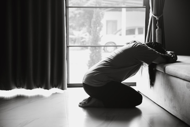 Schizofrenia con solitudine e tristezza nel concetto di depressione per la salute mentale donna depressa seduta contro il pavimento a casa con una stanza buia che si sente infelice le donne sono depresse, timorose e infelici