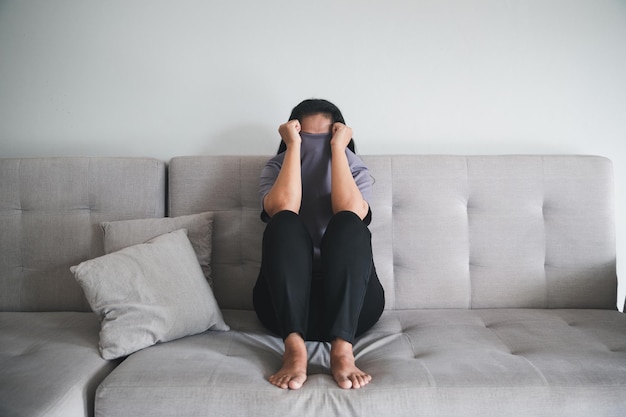 Schizophrenia with lonely and sad in mental health depression concept Depressed woman sitting against on the sofa at home with dark room feeling miserable Women are depressed fearful and unhappy