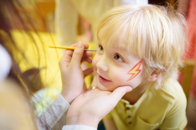 Schminken voor schattige kleine jongen tijdens kinderen vrolijkheid.