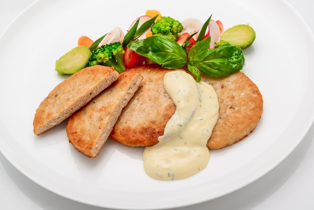 Schnitzel, chicken cutlet with white sauce and vegetables