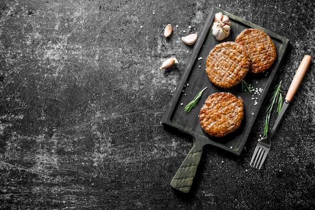 Schnitzels op een snijplank met knoflook en een vork