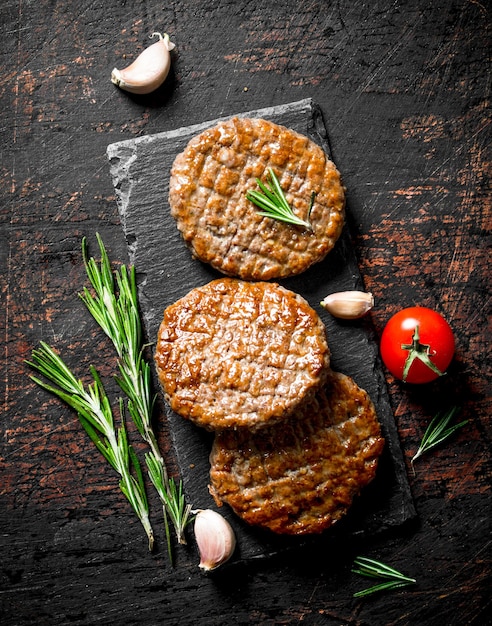 Schnitzels op een zwart stenen bord met stukjes knoflookrozemarijn en kersen