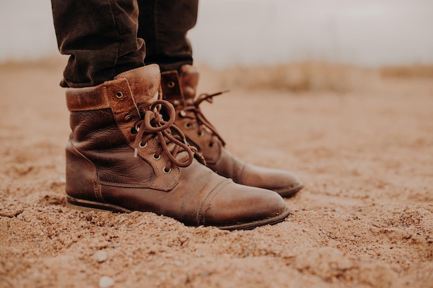 Schoeisel dat gerepareerd moet worden Man draagt oude schoenen met veters staat op de grond poseert buiten Bijgesneden opname Leren laars Wandelschoenen