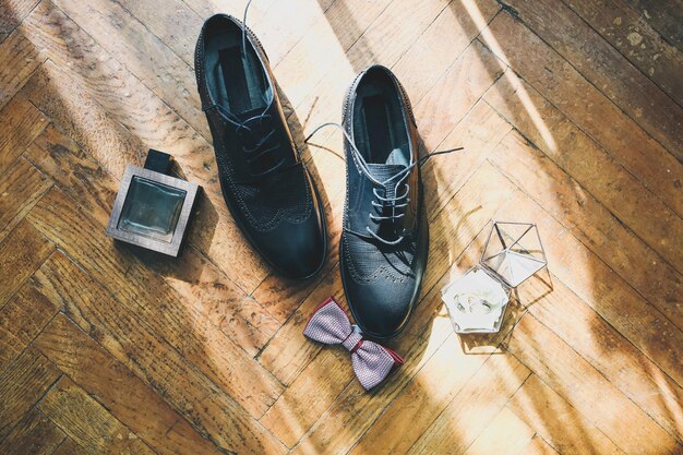 Schoenen bruidegom staan op de houten vloer Parfums met vlinderdas zijn vlakbij Trouwringen Stijlvolle vintage foto