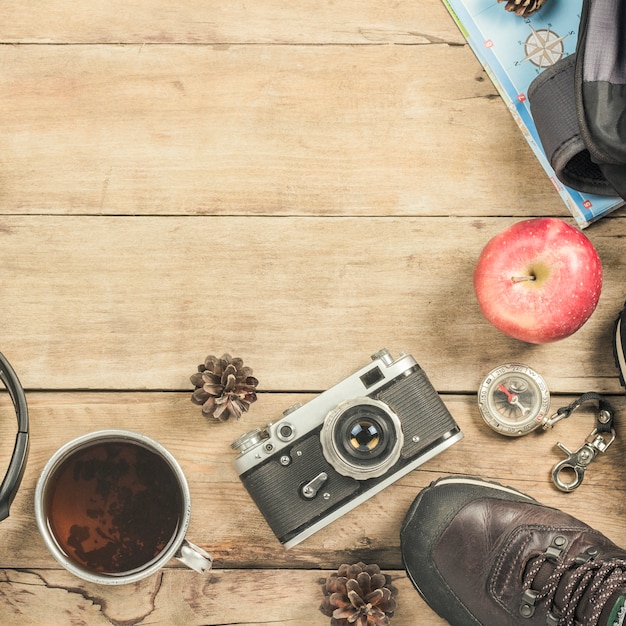 Schoenen, camera, mok met hete thee, rugzak, kaart en kompas op een houten oppervlak. Het concept van wandelen in de bergen of het bos, toerisme, tentrust. Plat lag, bovenaanzicht.