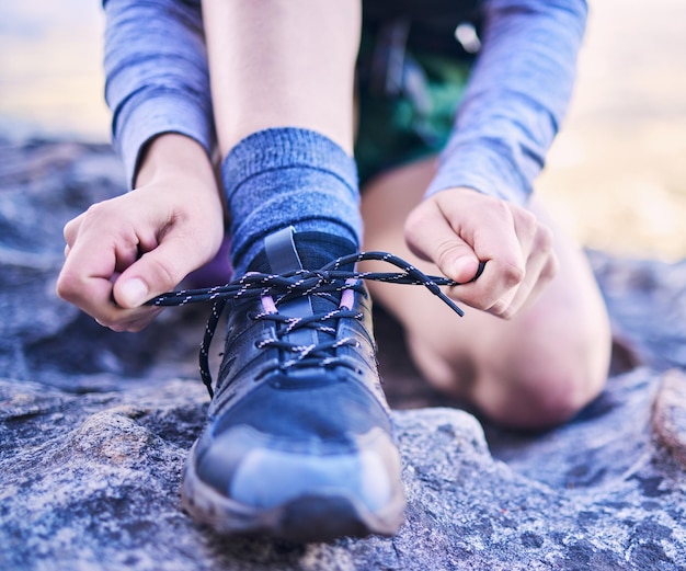 Schoenen veters strikken en een persoon voor fitness bergwandelen of beginnen met trainen voor sport Natuuroefening en close-up handen van een atleet met voeten en klaar voor hardlooptraining of cardio