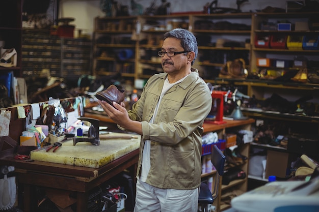 Schoenmaker die een schoen onderzoekt