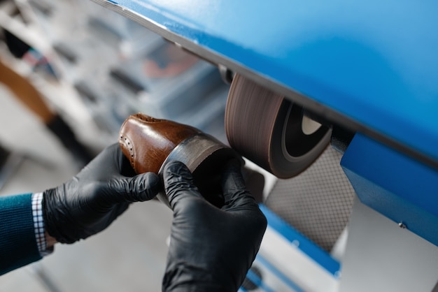 Schoenmaker verwerkt de schoen op amarilmachine, schoeiselreparatie