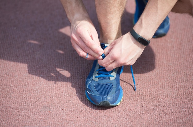 Schoenveters goed strikken. hardloopschoenen binden en rijgen. mannelijke handen kant sportschoen. atletisch schoeisel. schoenenwinkel. actieve levensstijl. een sterke knoop leggen door de schoenveter eromheen te wikkelen om een strik te maken.