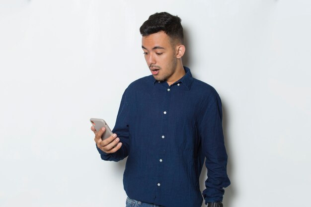 Schok jonge zakenman met behulp van mobiele telefoon geïsoleerd op een witte achtergrond