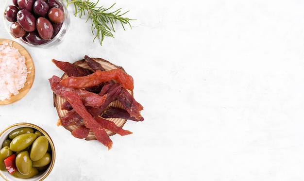 Schokkerige vleesreepjes met kruiden, olijven, snack voor bier op houten plaat