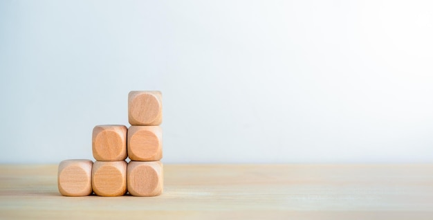 Schone houten kubusblokken gestapeld als bedrijfsdiagram stappen geïsoleerd op houten bureau witte achtergrond met kopieerruimte bedrijfsgroei grafiek proces banner doel succes en economische verbetering concepten