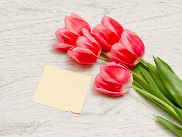 Schone kaart, roze tulpen op een lichte houten achtergrond. bovenaanzicht, ruimte voor tekst