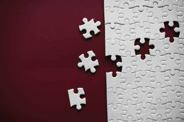 Schone puzzelelementen op de rode achtergrond Leeg puzzelstukje op tafel Teamwork concept