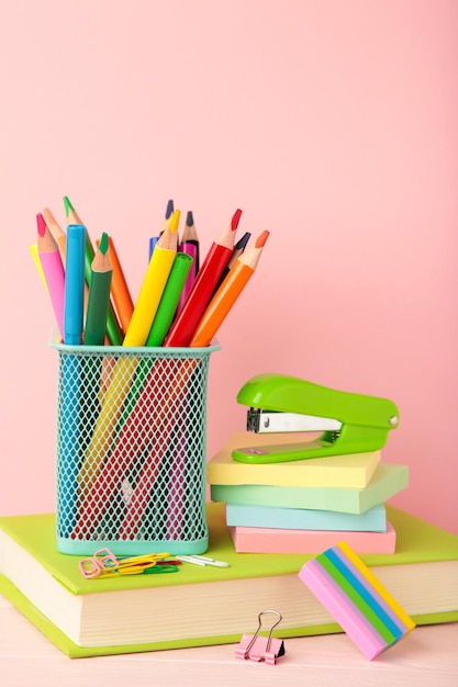 School accessories with books on pink background Back to school concept Vertical photo